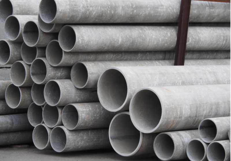 Asbestos-cement pipes of different sizes and diameters for sewage systems, engineering works and wells for sale in a warehouse. Concrete products for construction